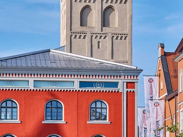 Bunte Häuserfassade der Langen Zeile mit dem roten Schrannengebäude im Hintergrund